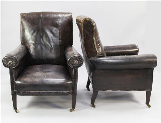 A pair of high back brown leather armchairs,